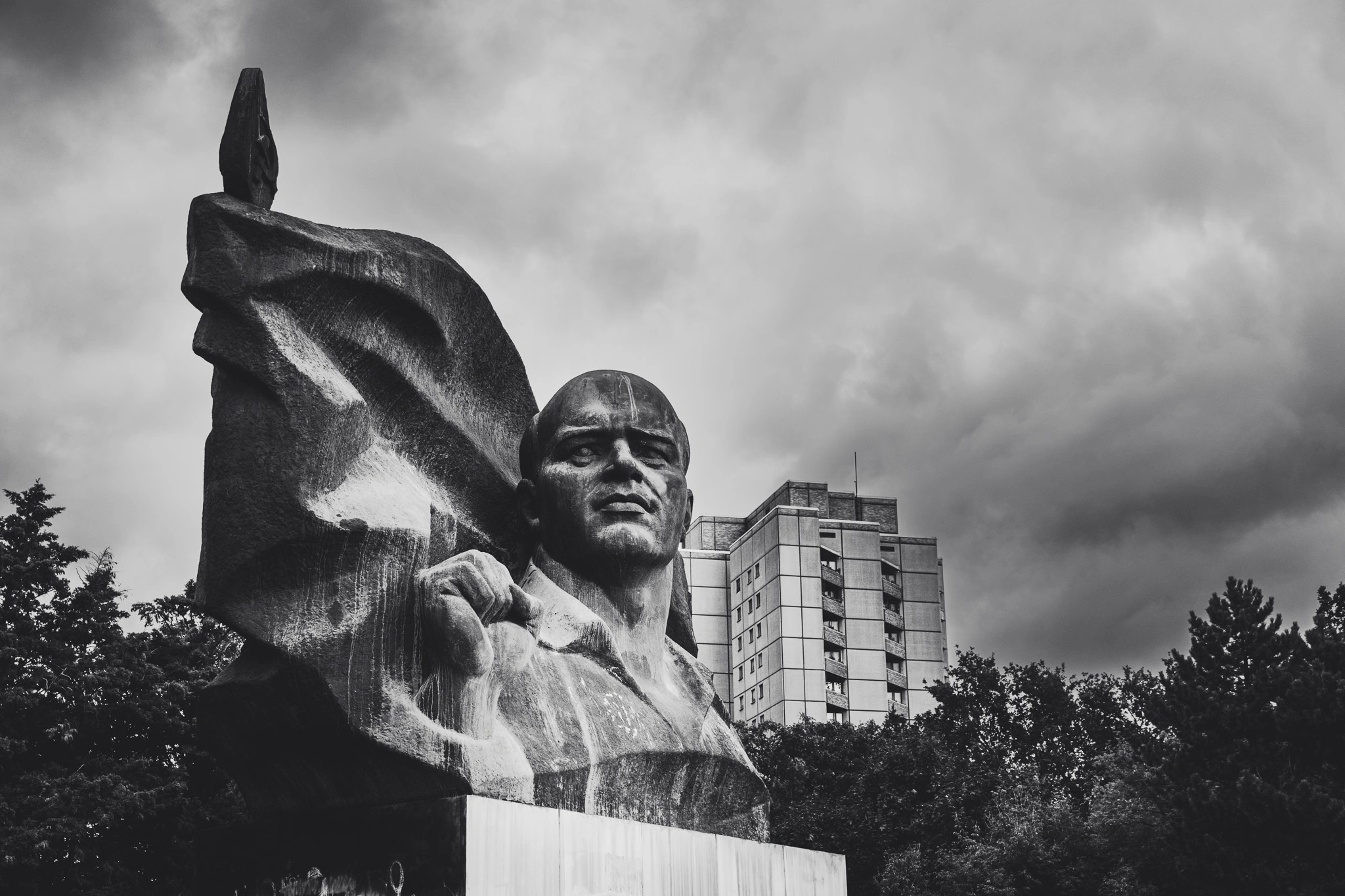 Ernst Thälmann monument with raised fist in front of a Plattenbau, black and white