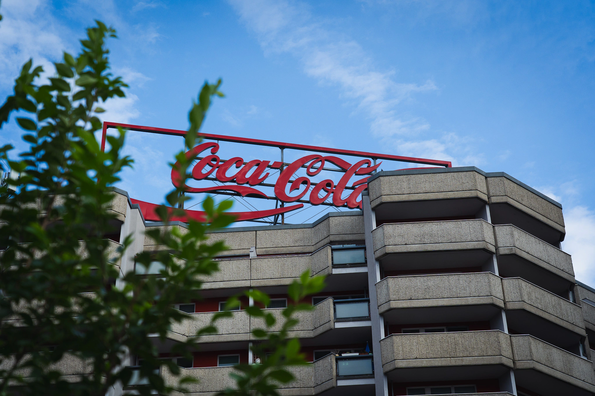 Red Coca-Cola rooftop sign on a concrete apartment building