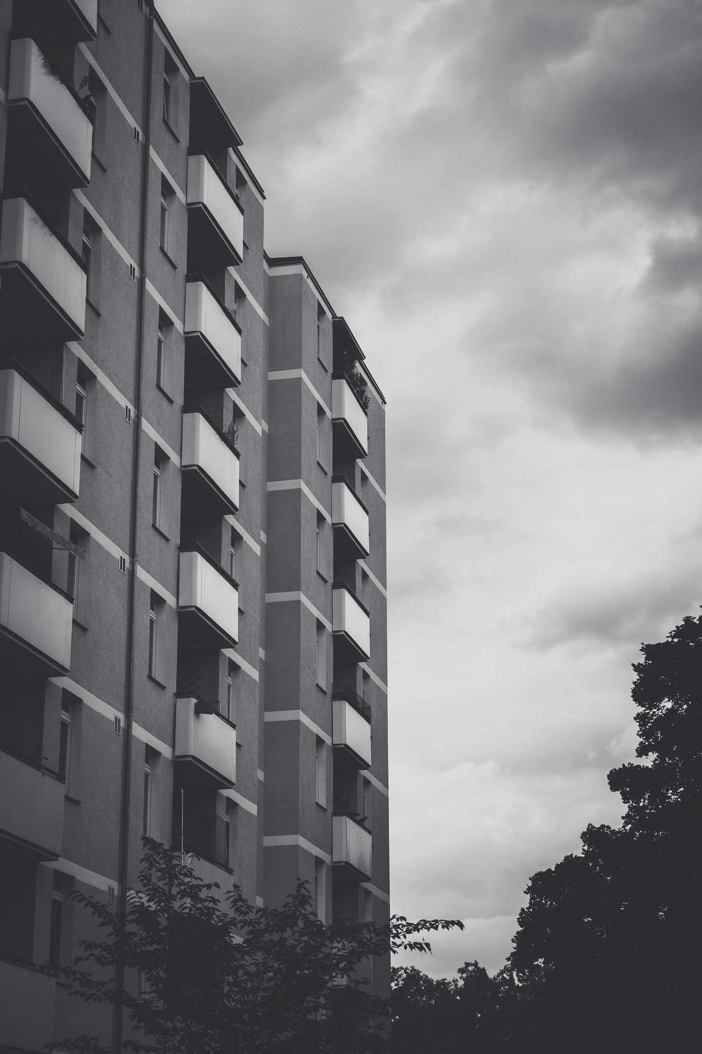 Apartment block with stacked balconies under a moody sky, black and white