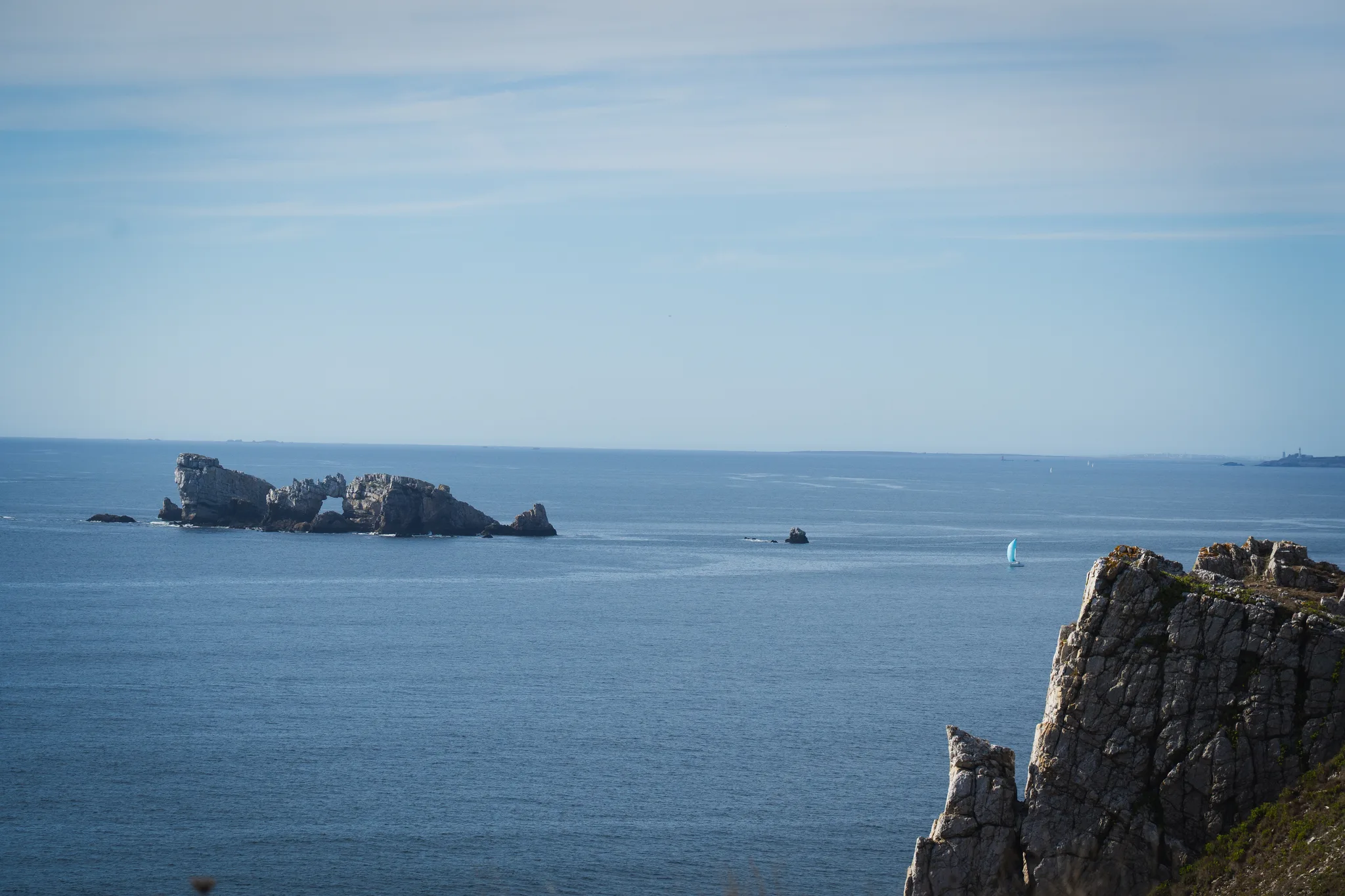 Château de Dinan rock with a single sailboat on the horizon