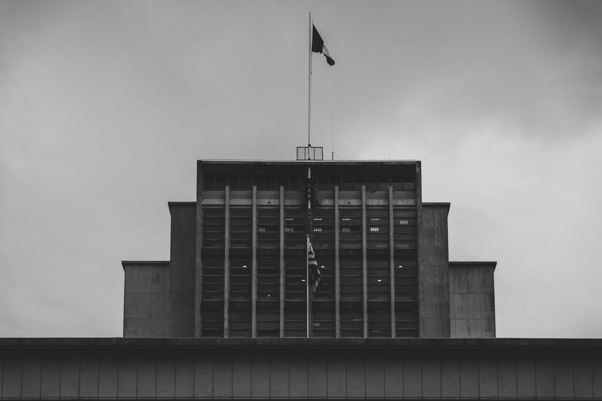 The stepped concrete top of Brest city hall with a flag, black and white