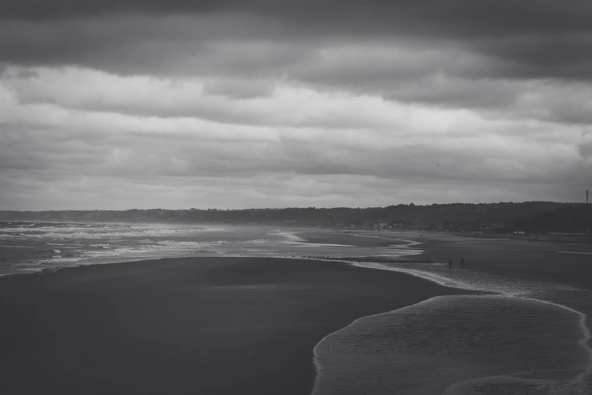 Wet sand and breaking waves under a dark sky, black and white