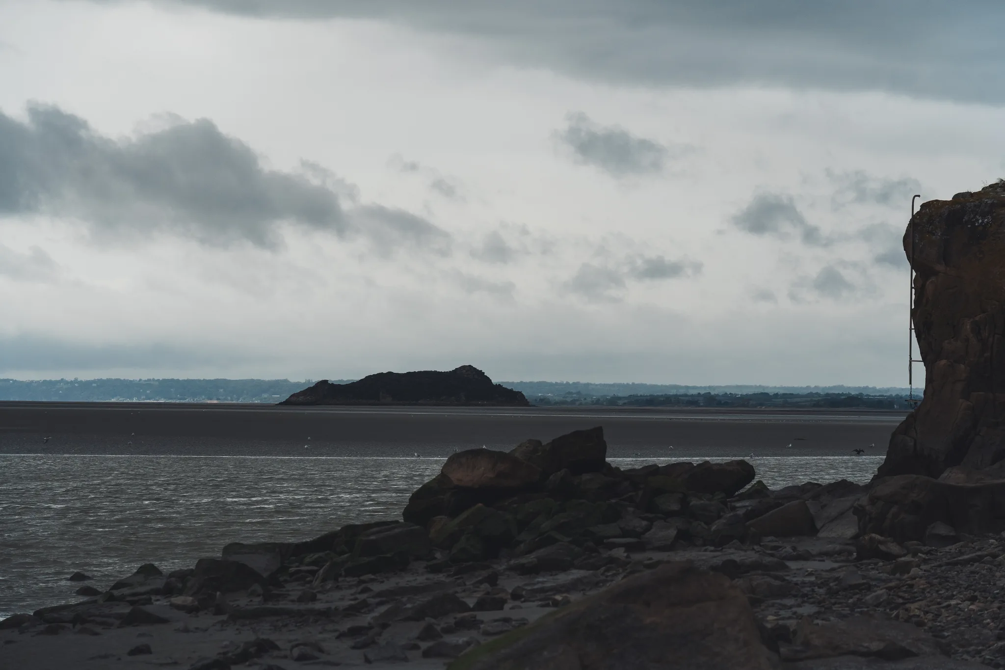 Rocky shore and Tombelaine island in the bay at low tide