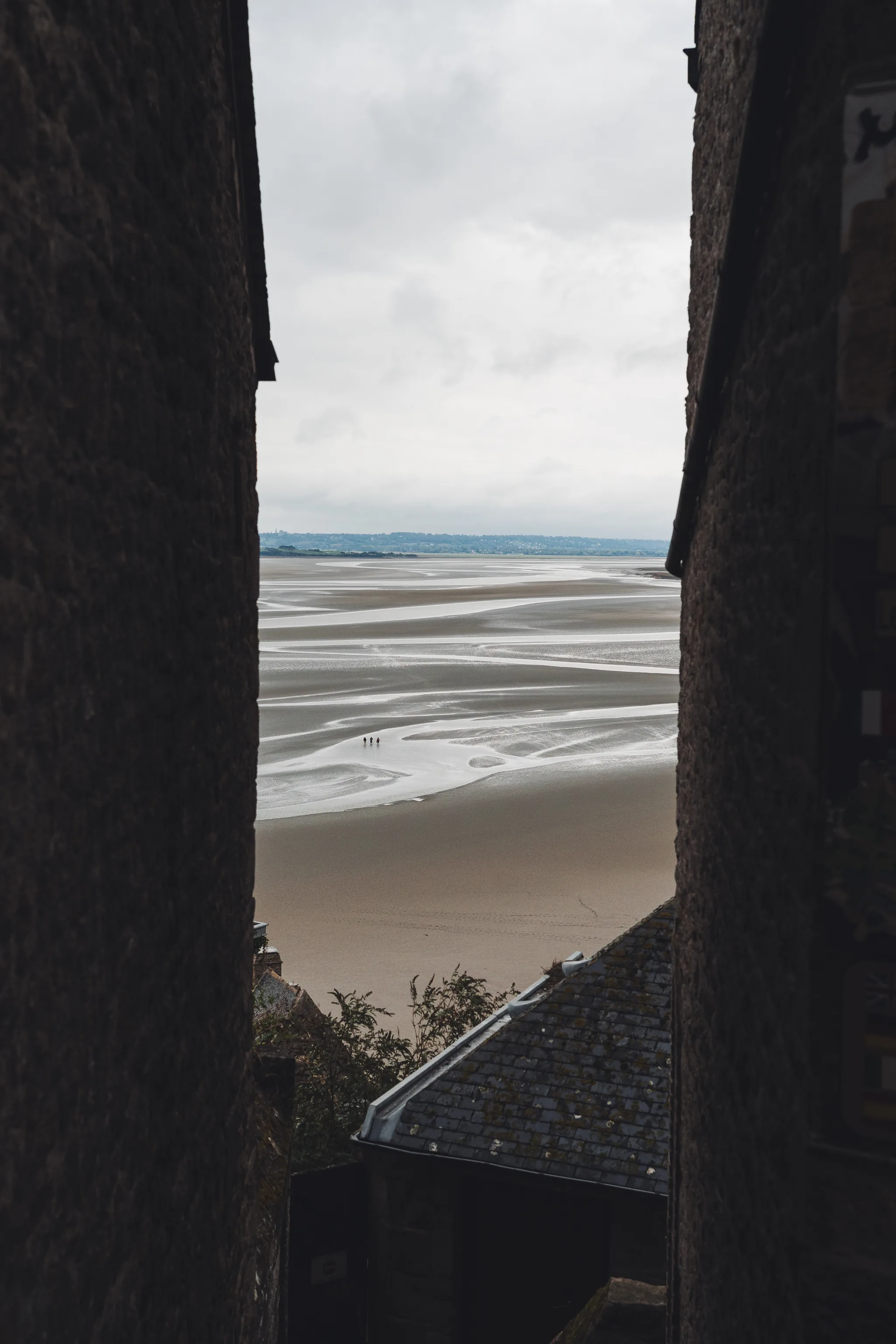 View between two dark walls down onto the sand flats of the bay