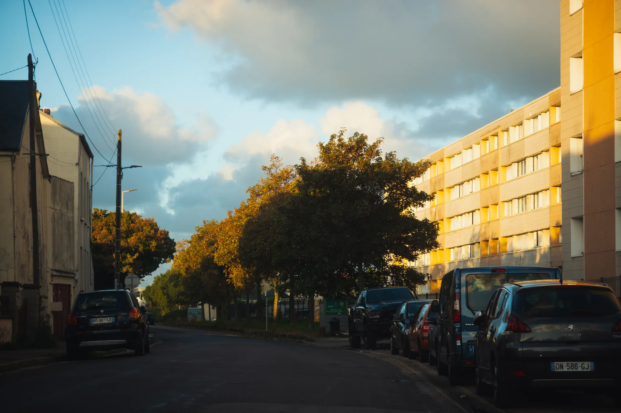 Street of houses and an apartment block lit by low morning sun