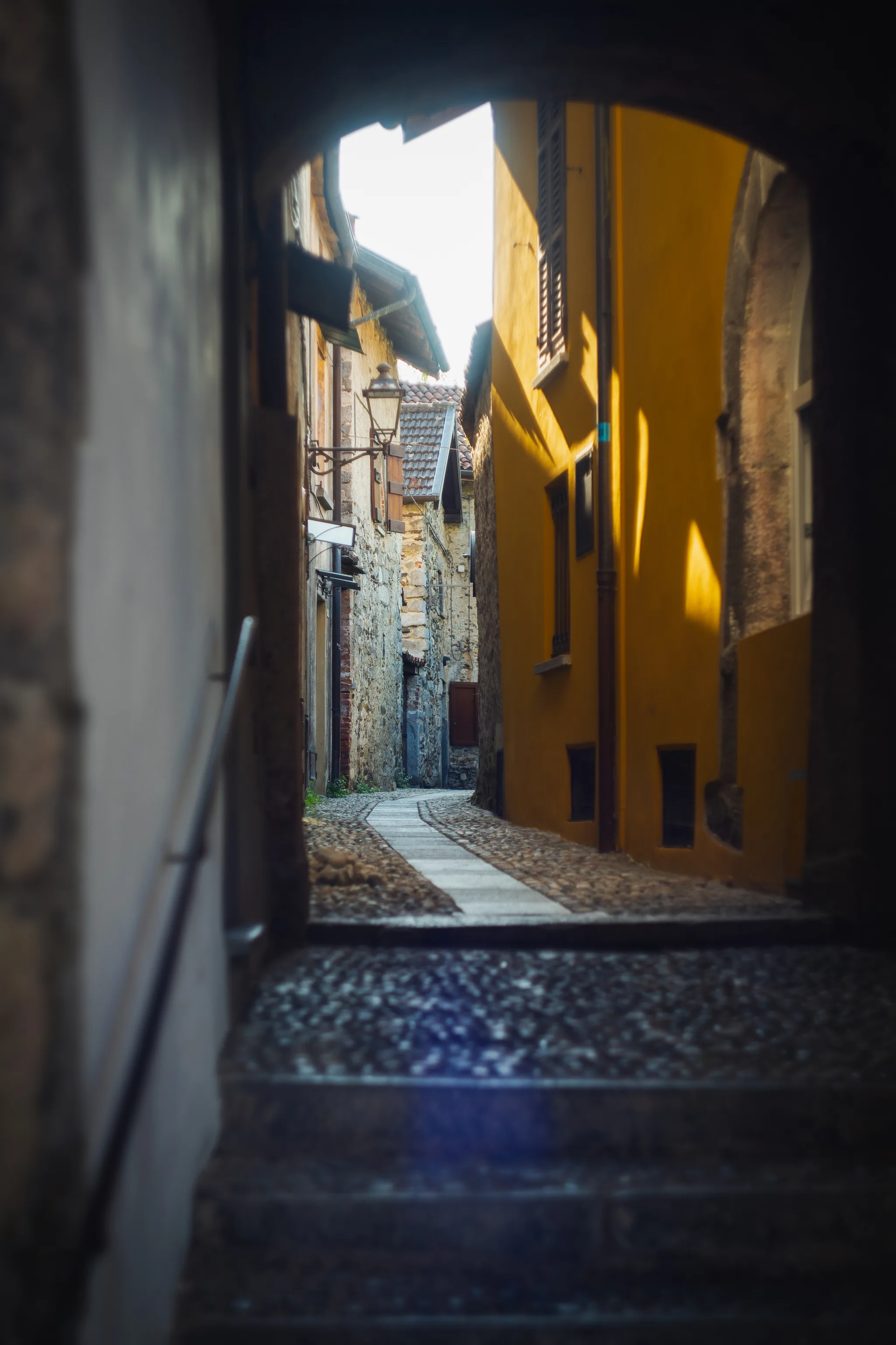 View through a dark archway into a lane with a bright yellow wall