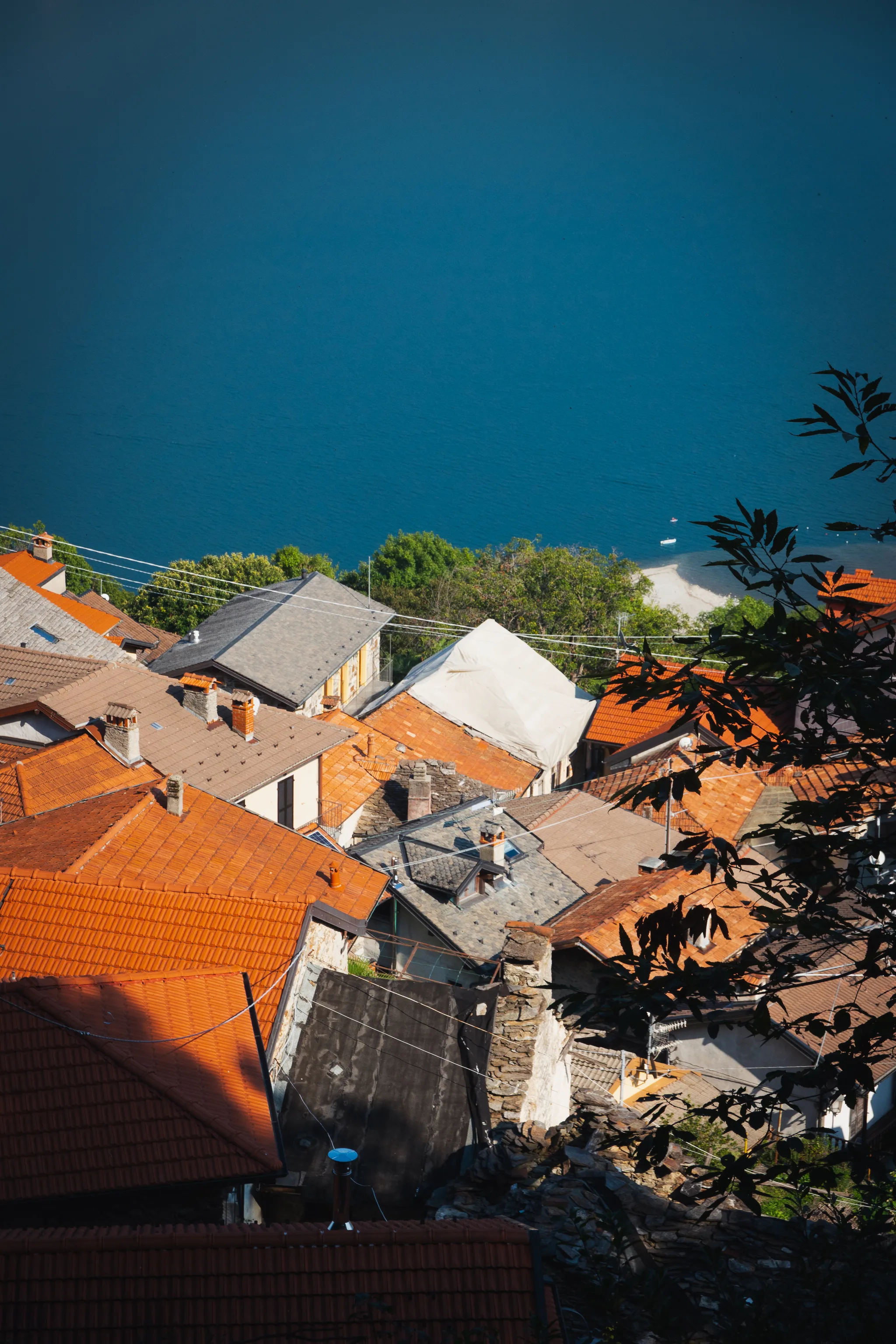 Orange and grey roofs seen from above, deep blue lake behind