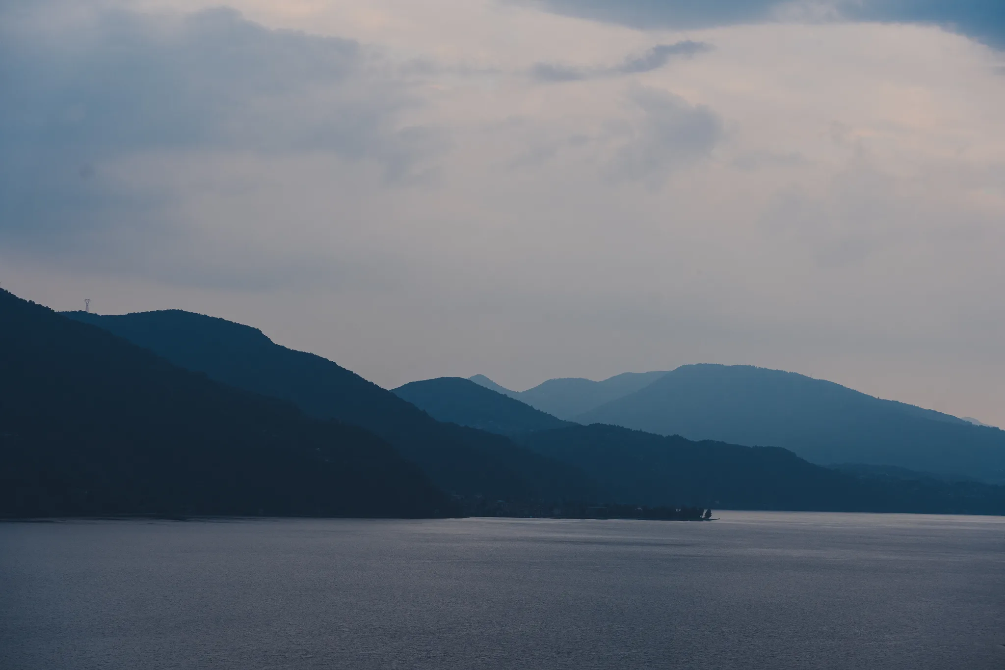 Layered blue ridges above the lake under an overcast evening sky